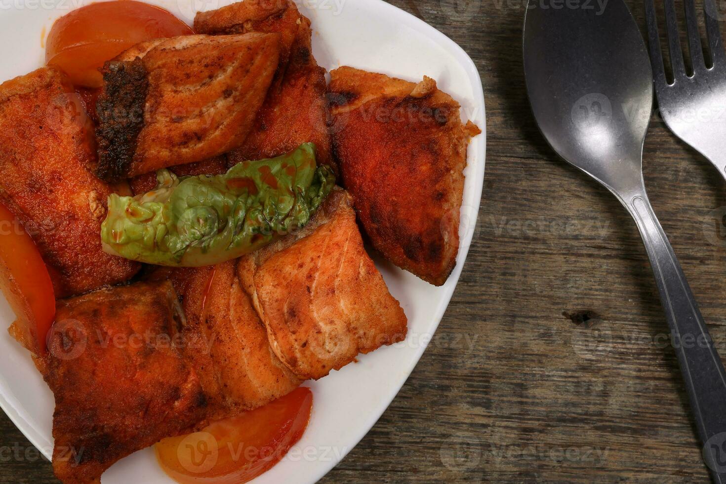 Pan friend salmon fish fillet in white triangular plate spoon on rustic wood background photo