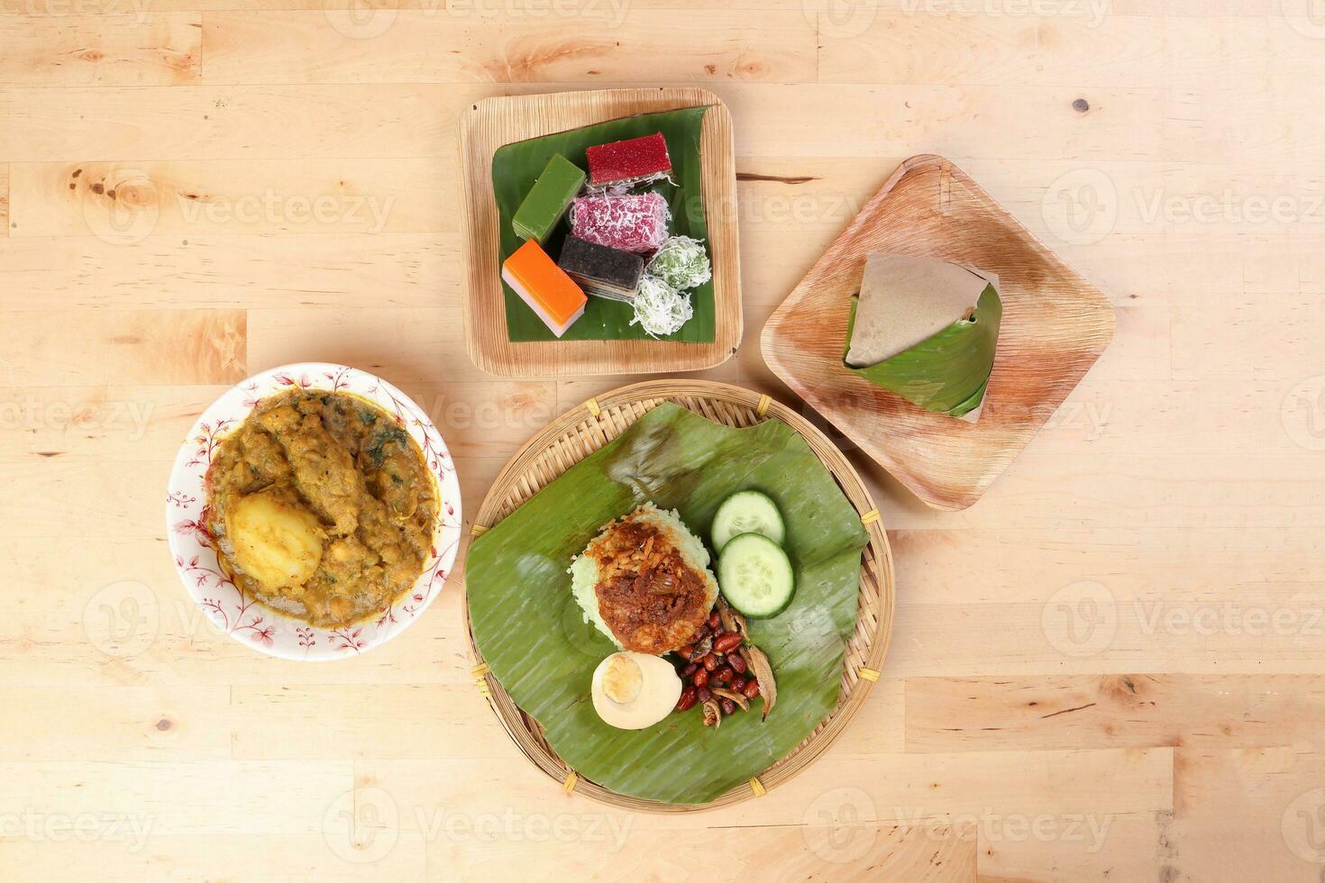 Nasi Lemak fragrant rice coconut milk with sambal friend peanut anchovy egg packed banana leaf round bamboo plate colorful nyonya kuih sweet desert palm leaf plate on wooden background photo