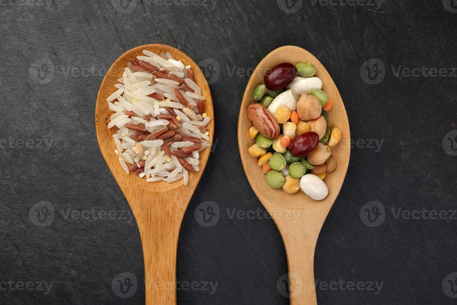 Mixed beans multi grain low glycaemic index healthy rice grain basmati millet buckwheat red rice in wooden spoon on black background photo