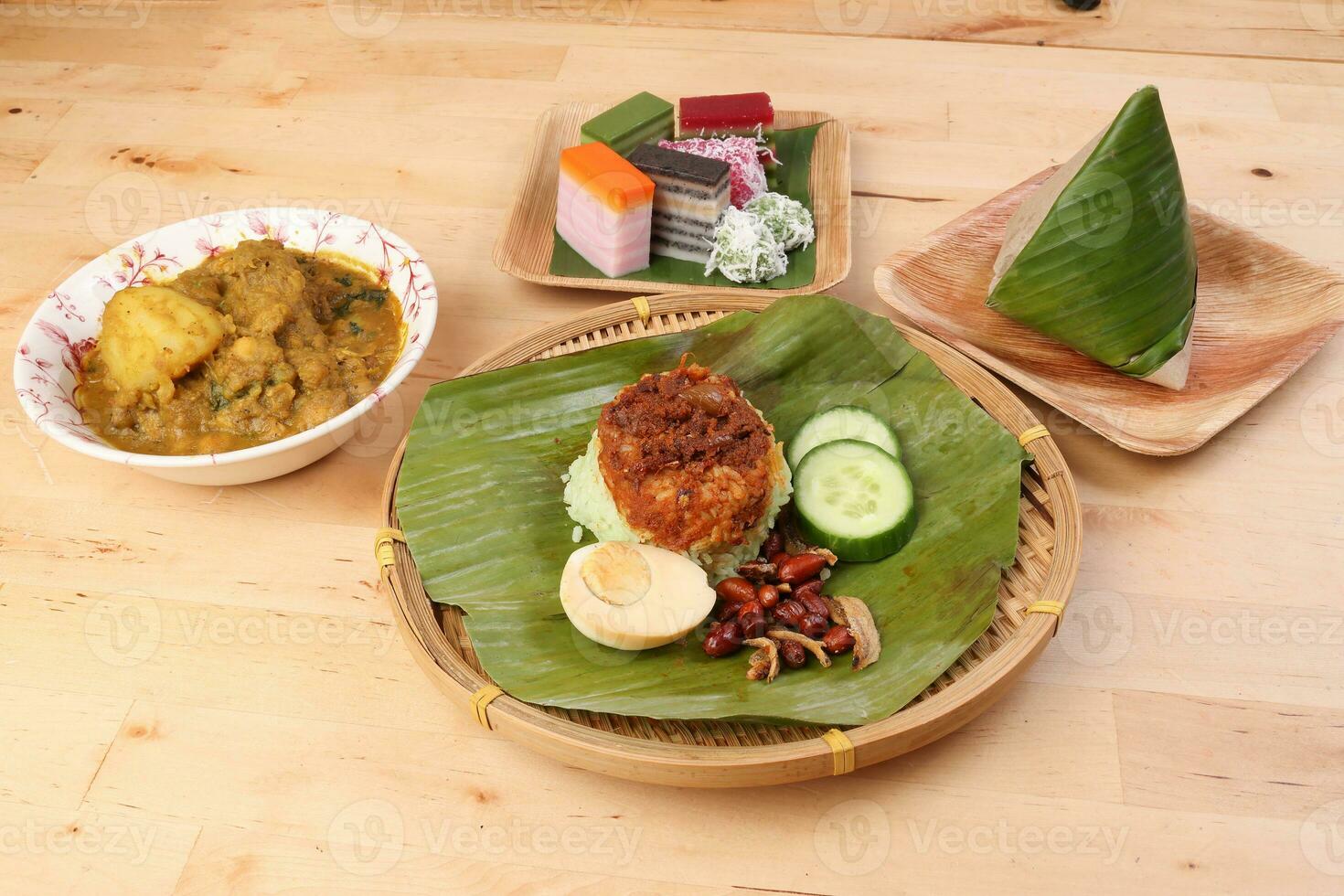 Nasi Lemak fragrant rice coconut milk with sambal friend peanut anchovy egg packed banana leaf round bamboo plate colorful nyonya kuih sweet desert palm leaf plate on wooden background photo