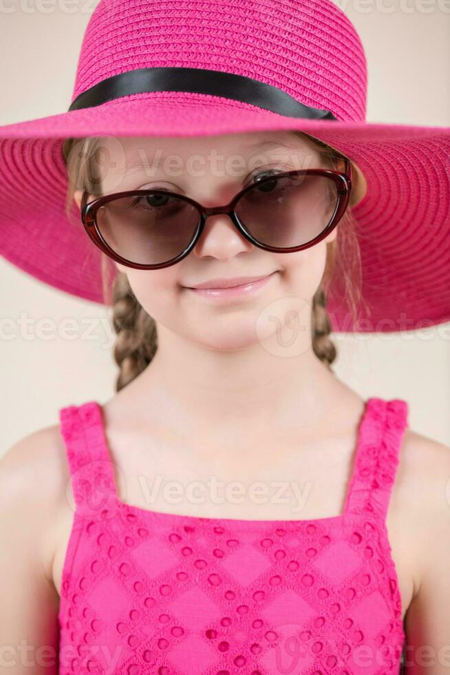 pequeño niña con rosado vestir sombrero y Gafas de sol foto