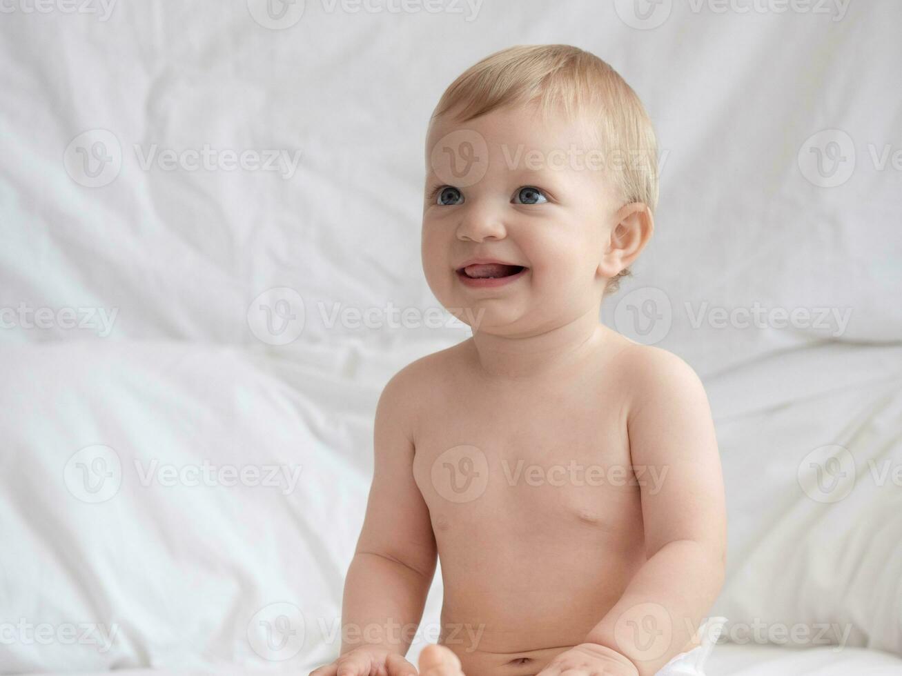 linda bebé sentado y sonriente en el cama foto