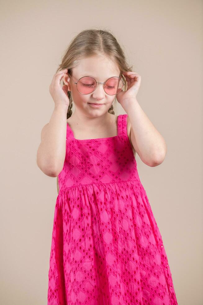 Portrait of a cute little girl in pink dress and pink glasses photo