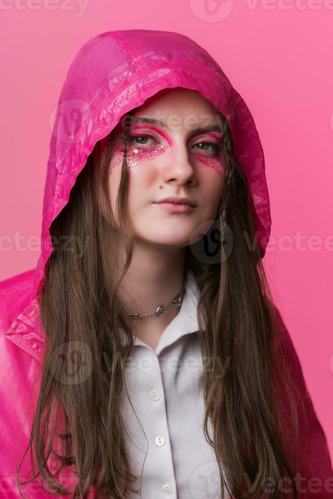 Portrait of informal young adult woman with pink stage make-up painted on face, looking at camera photo