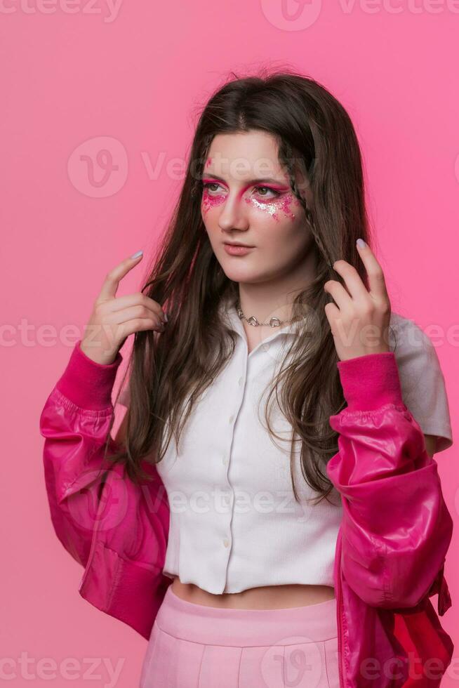 Portrait of young woman with pink stage make-up on face, dressed in pink jacket and white t-shirt photo