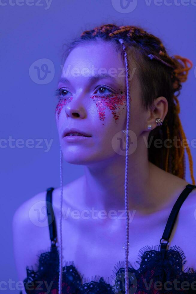 Cinematic night portrait of woman face with shiny make-up with sequins illuminated neon light photo