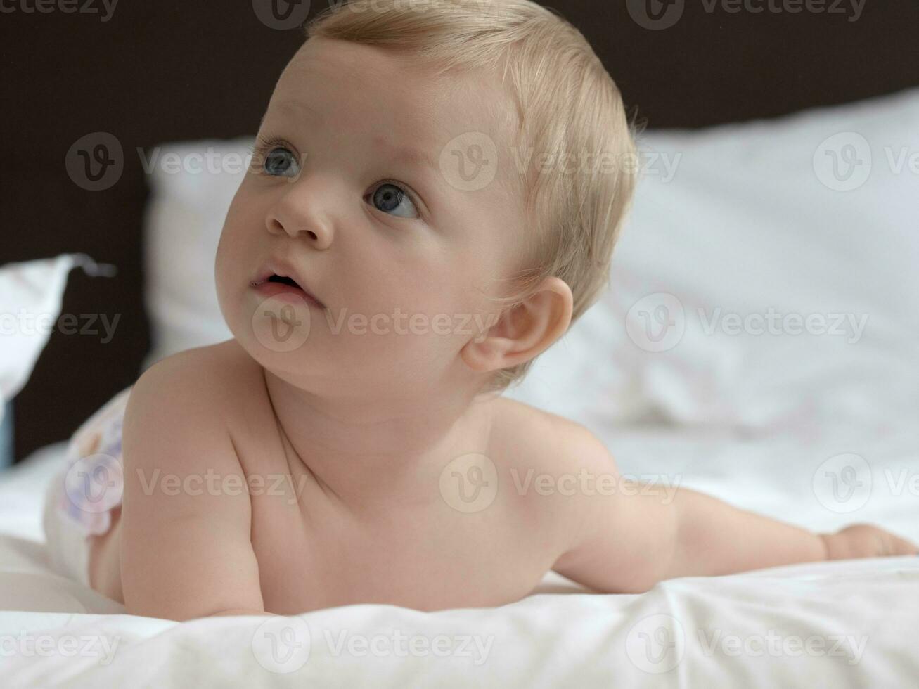 Blond blue eyes baby on the bed photo