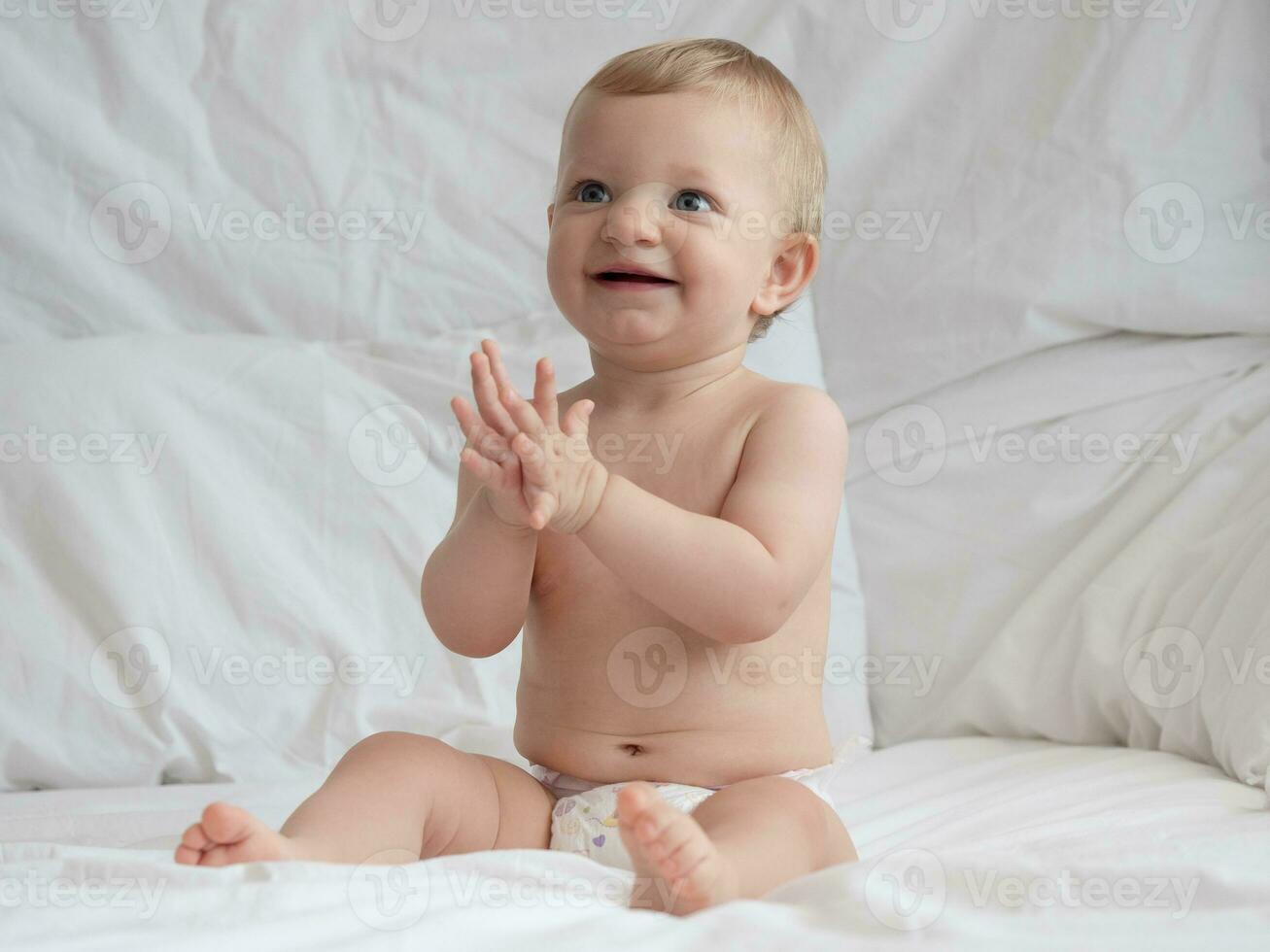 linda bebé sentado y sonriente en el cama foto