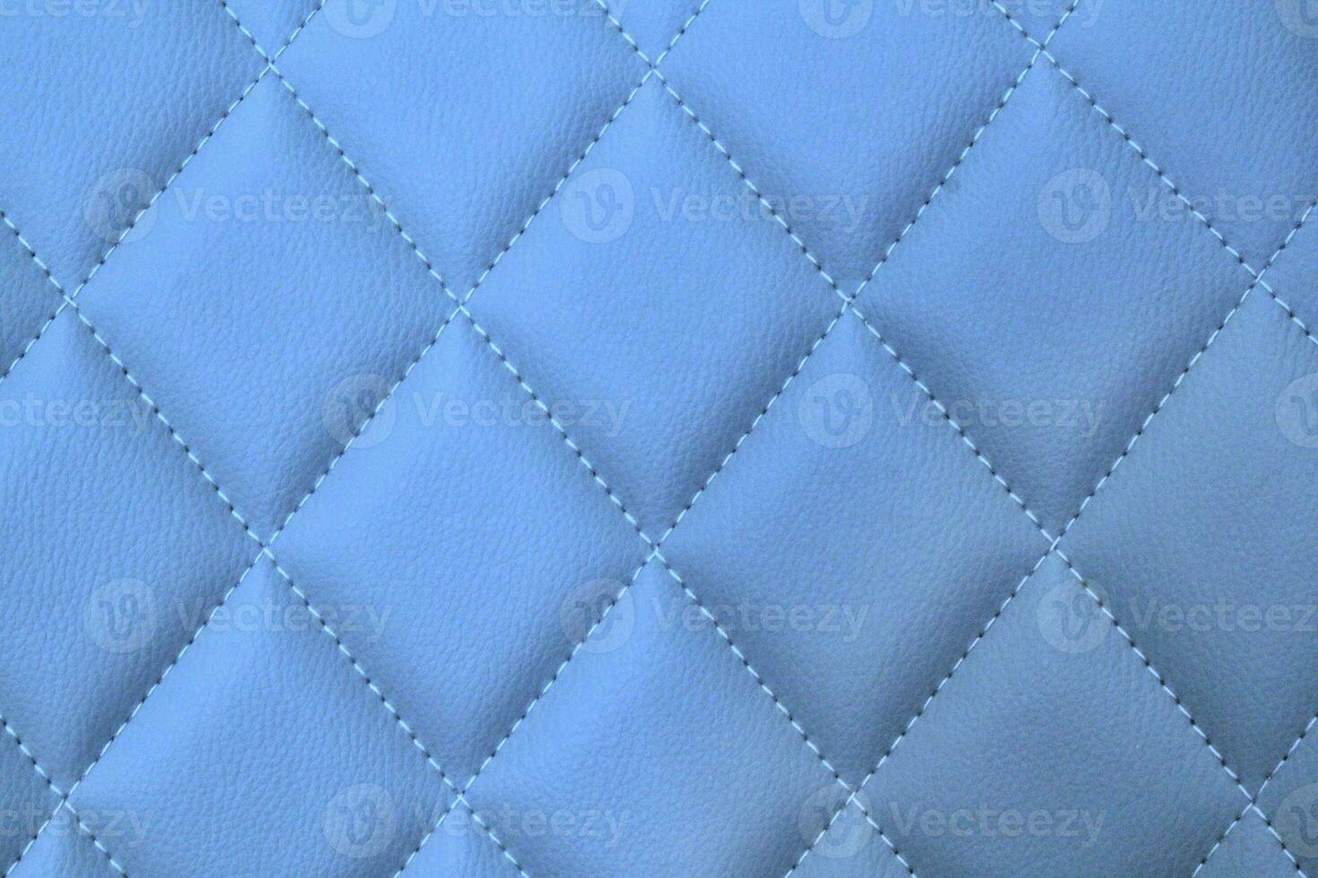 Close-up texture of blue stitched threads leather with seam background. Rhombus pattern for interior car, sofa, wall covering, headboard. Natural material on furniture backdrop. Classic design photo