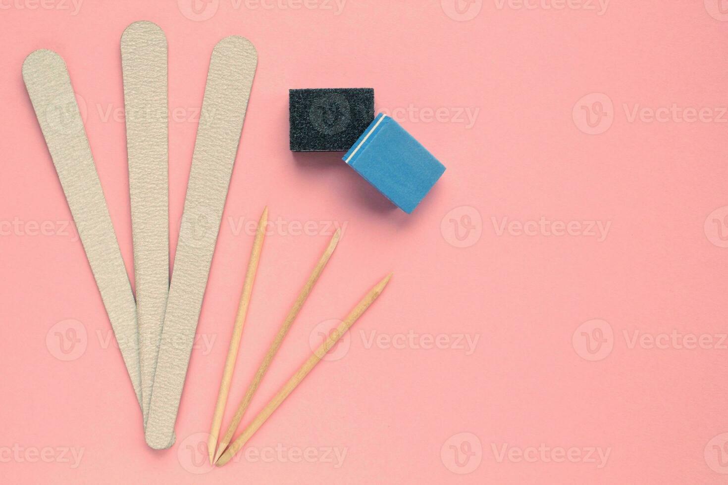 Different abrasive nail polishing files and wooden sticks on pink background. Manicure and pedicure instruments set . Cosmetic accessories hygiene equipment. Beauty spa salon, hand care concept photo