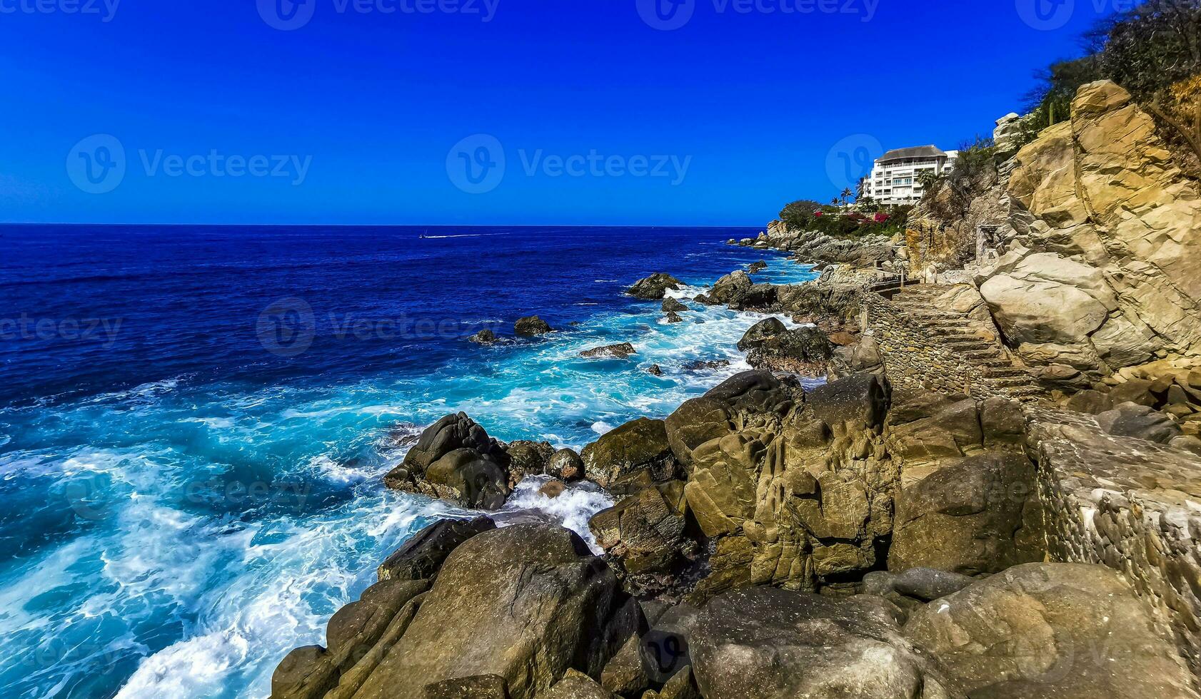 Surfer waves turquoise blue water rocks cliffs boulders Puerto Escondido. photo