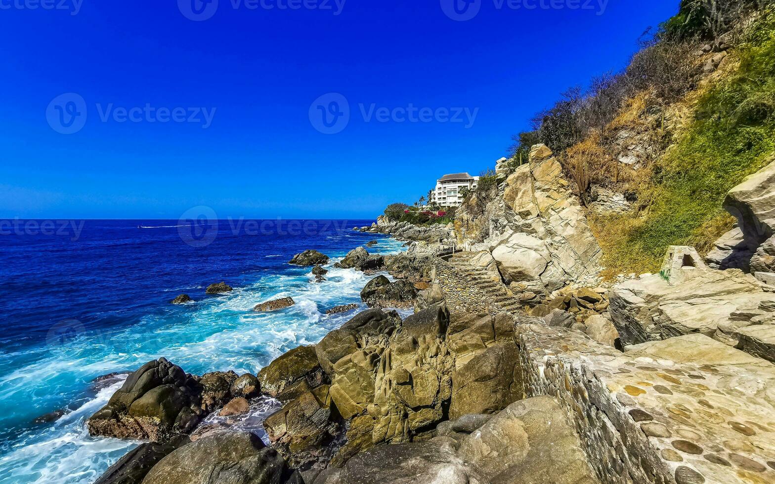Surfer waves turquoise blue water rocks cliffs boulders Puerto Escondido. photo
