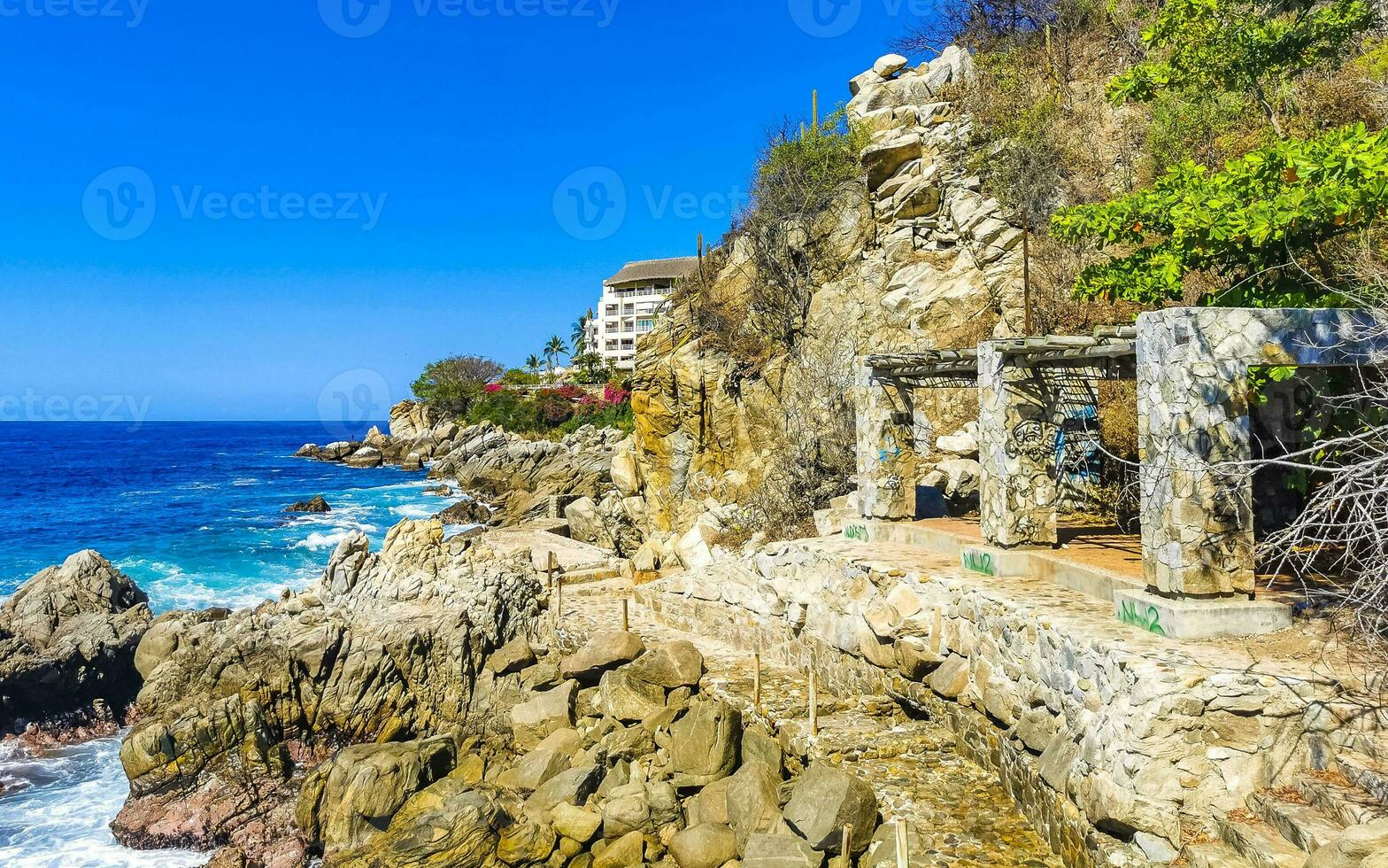 Surfer waves turquoise blue water rocks cliffs boulders Puerto Escondido. photo