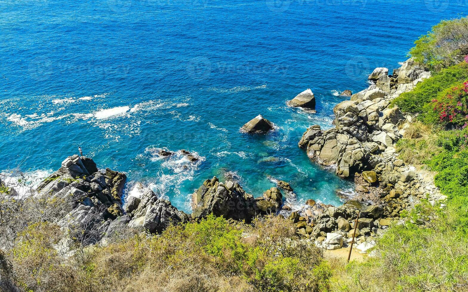 Surfer waves turquoise blue water rocks cliffs boulders Puerto Escondido. photo