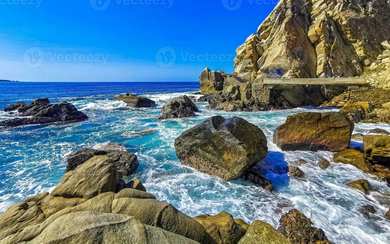 Surfer waves turquoise blue water rocks cliffs boulders Puerto Escondido. photo