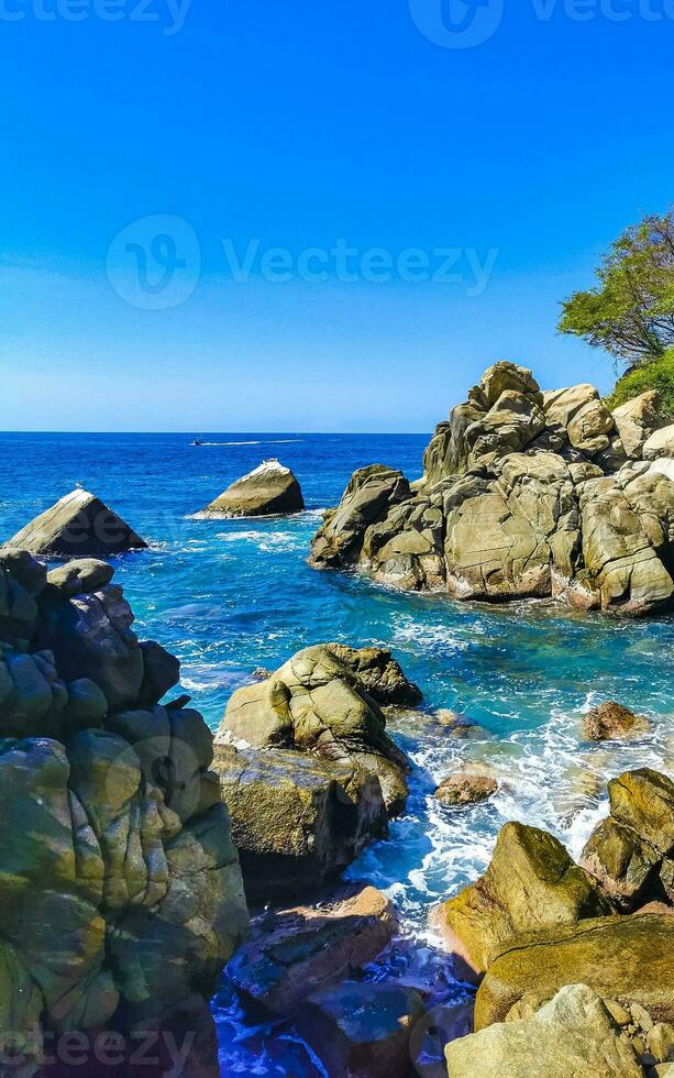 Surfer waves turquoise blue water rocks cliffs boulders Puerto Escondido. photo