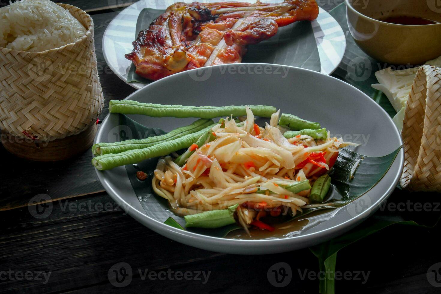 tailandés comida plato ambos en Tailandia y Asia papaya ensalada o como nosotros llamada eso somtum es complementado con A la parrilla pollo y pegajoso arroz con Fresco frituras. servido en el negro de madera mesa. foto