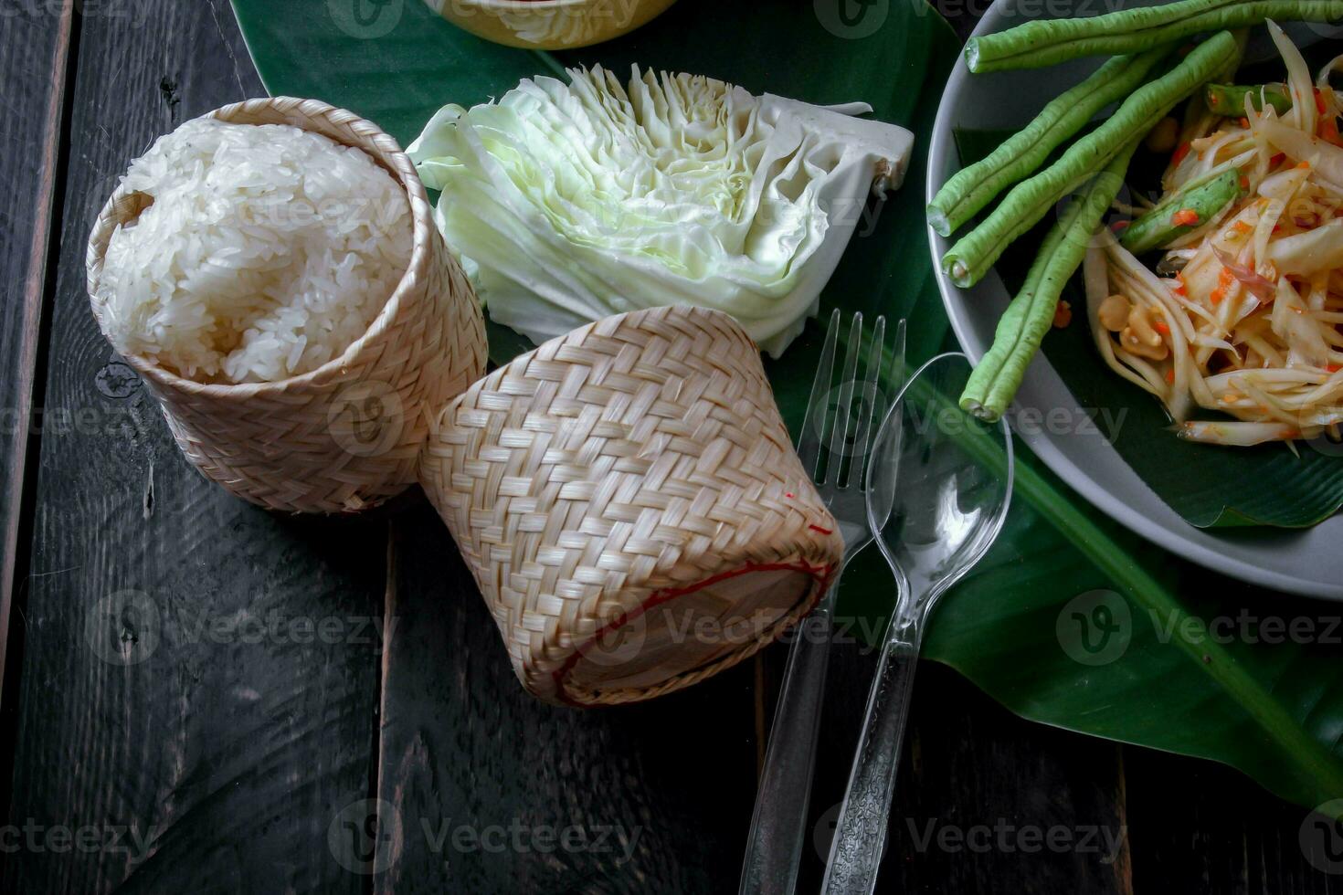 tailandés comida plato ambos en Tailandia y Asia papaya ensalada o como nosotros llamada eso somtum es complementado con A la parrilla pollo y pegajoso arroz con Fresco frituras. servido en el negro de madera mesa. foto