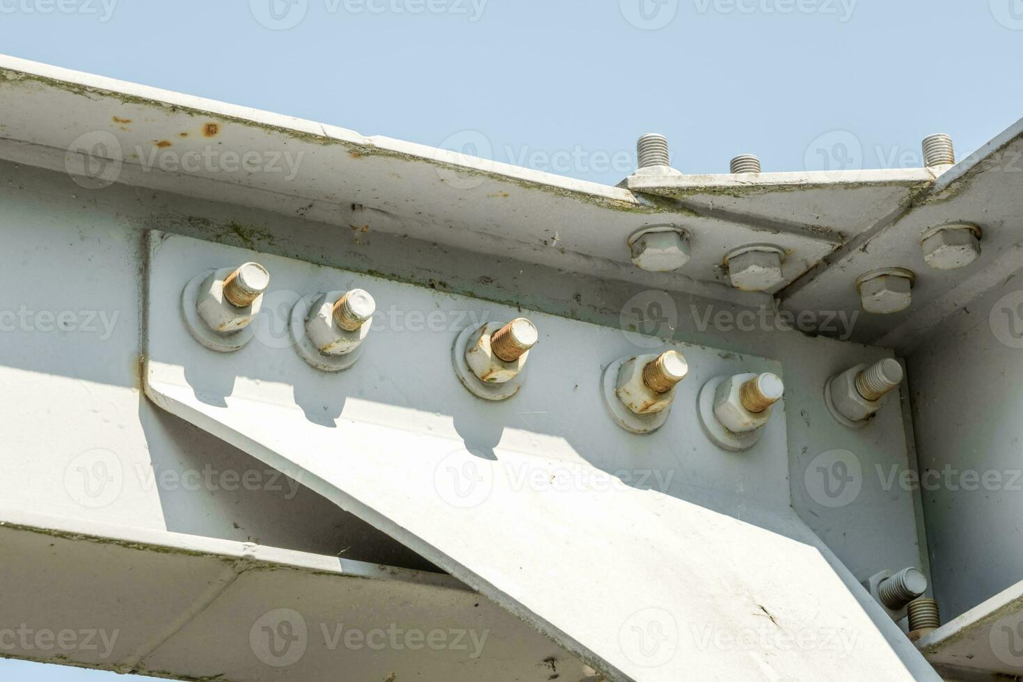 Bolts and nuts on metal plates of steel structure of heavy duty straight crossbar of frame and bridge support photo