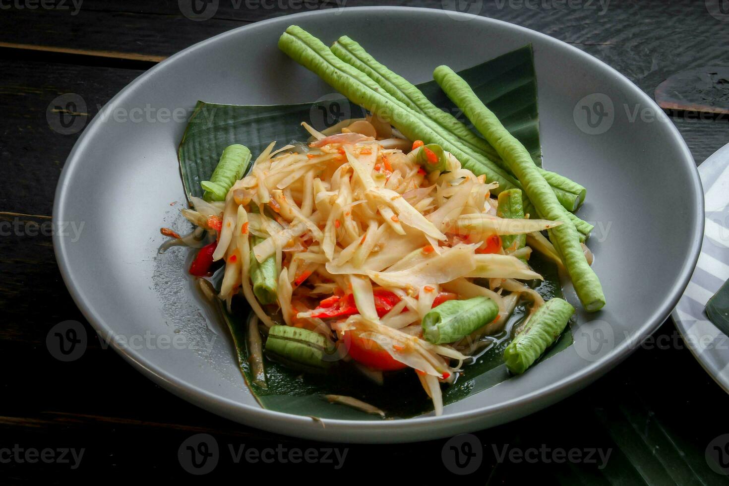 tailandés comida plato ambos en Tailandia y Asia, papaya ensalada o como nosotros llamada eso somtum es complementado con A la parrilla pollo y pegajoso arroz con Fresco frituras. servido en el negro de madera mesa. foto