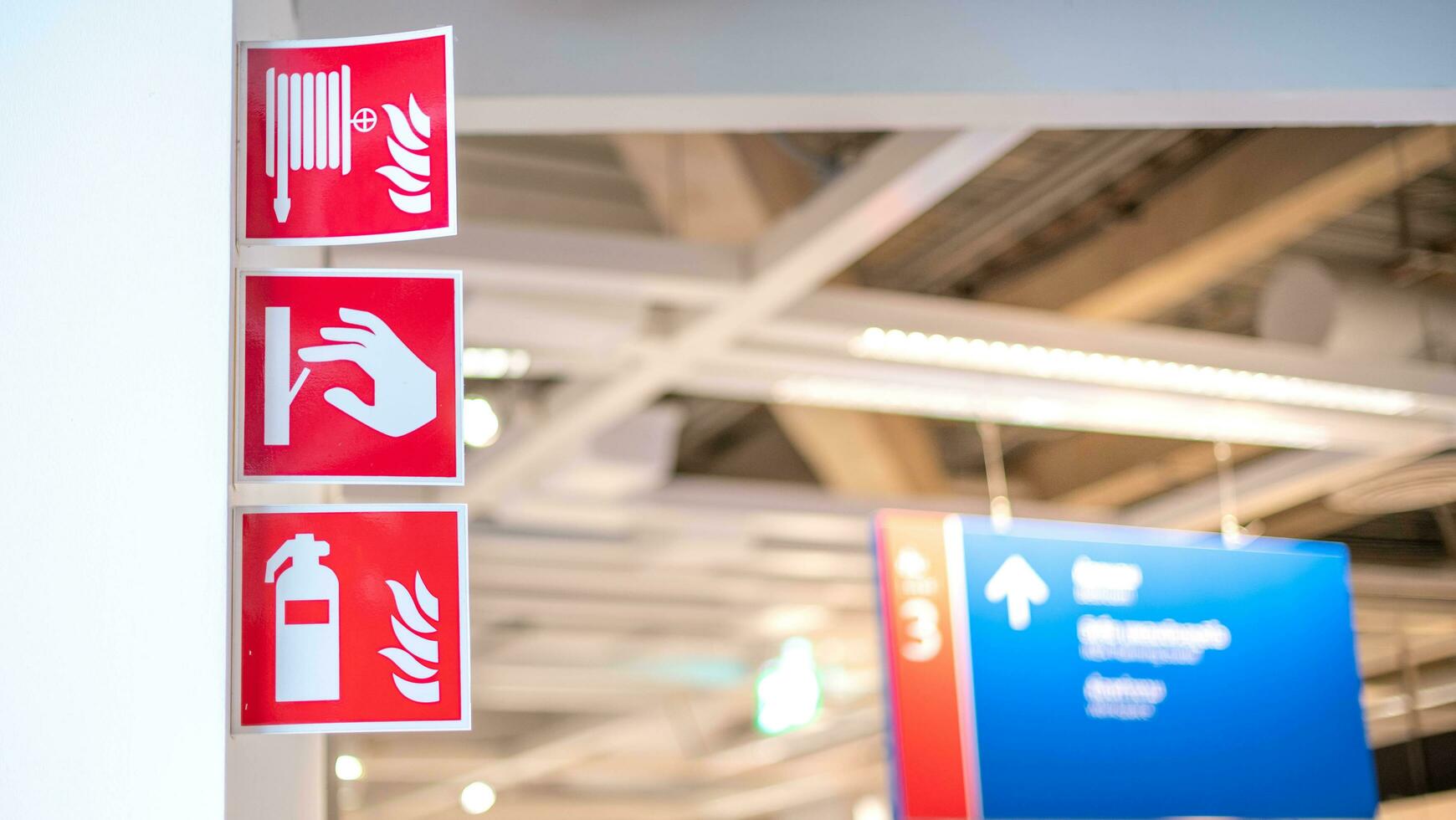 A red emergency fire exit direction plate that installed on the white door at the department store. photo