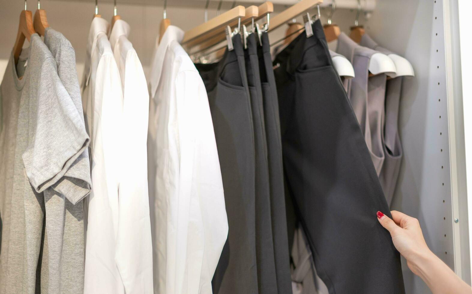 Female hand choosing clothes for checked pattern trouser on the rack in cloth shop at a department store. Check price, discount, and promotion of clothing products. photo