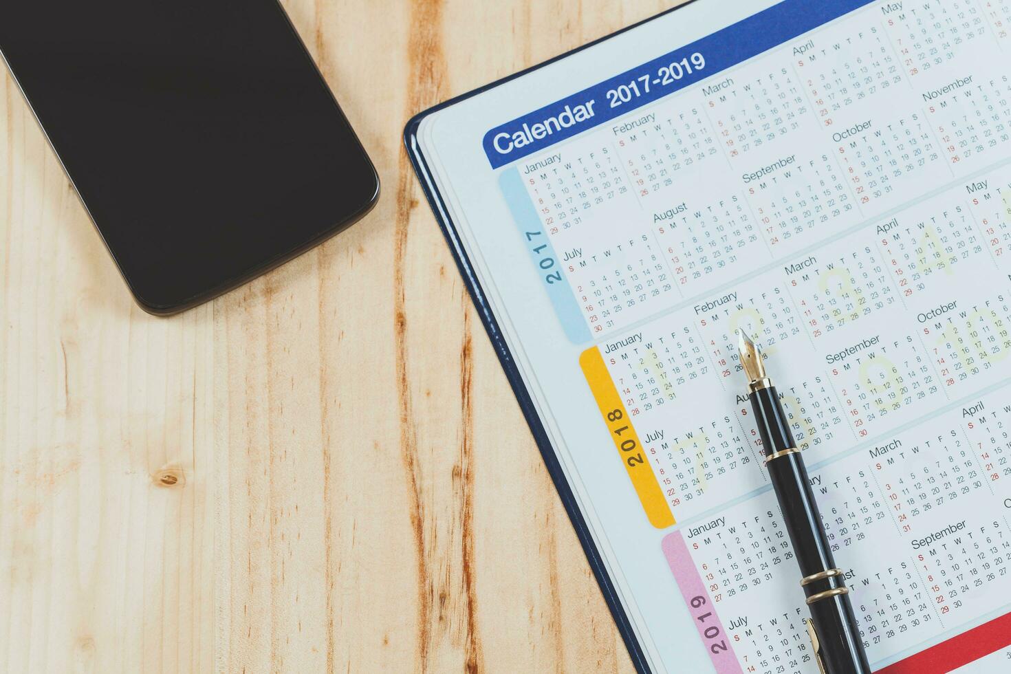 Calendar planner with fountain pen and hot coffee on wood table.office tool. photo