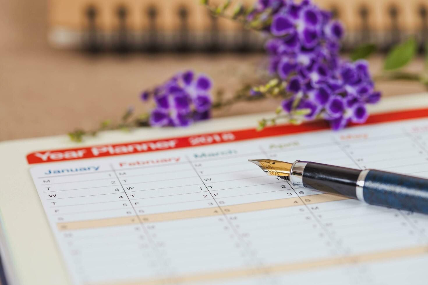 personal organizer or planner with fountain pen on wood table. photo