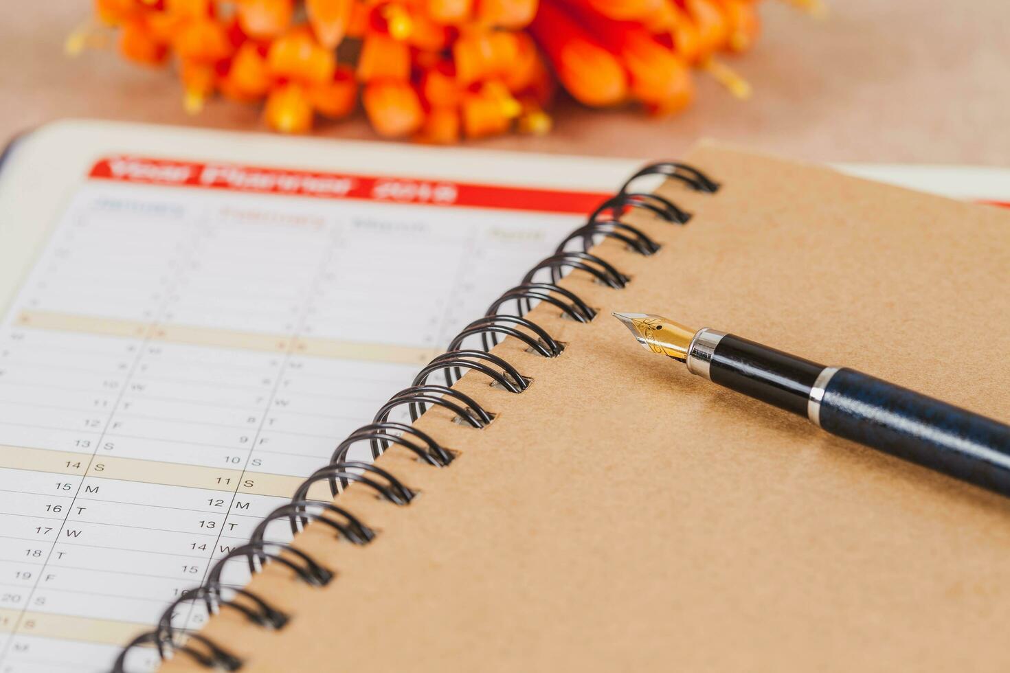 personal organizer or planner with fountain pen on wood table. photo