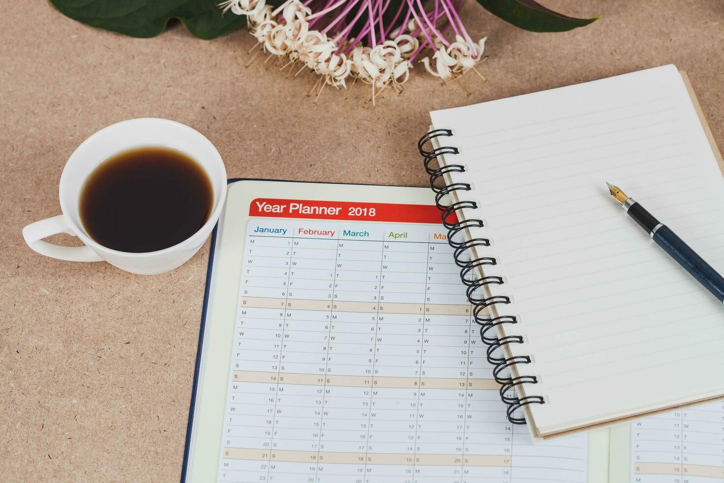 personal organizer or planner with fountain pen and hot coffee on wood table. photo