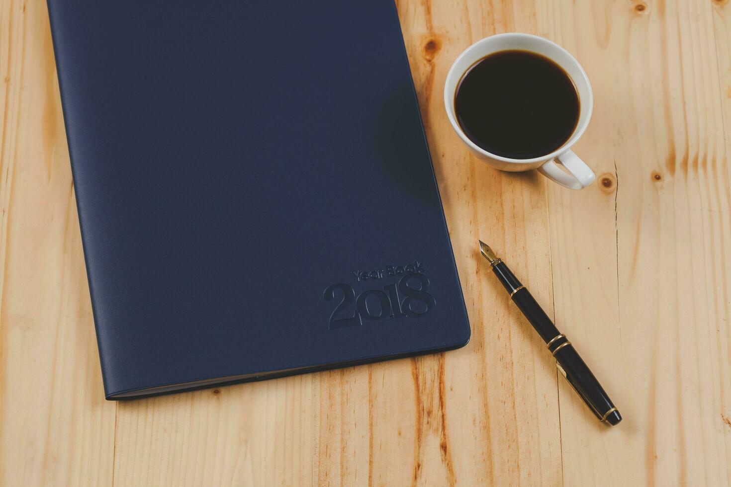 personal organizer or planner with fountain pen and hot coffee on wood table. photo