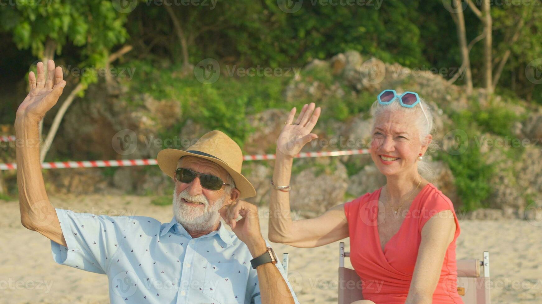 A couple of elderly sitting in chairs at the beach watching the sun and the sea on their summer vacation and they smile and enjoy their vacation. photo
