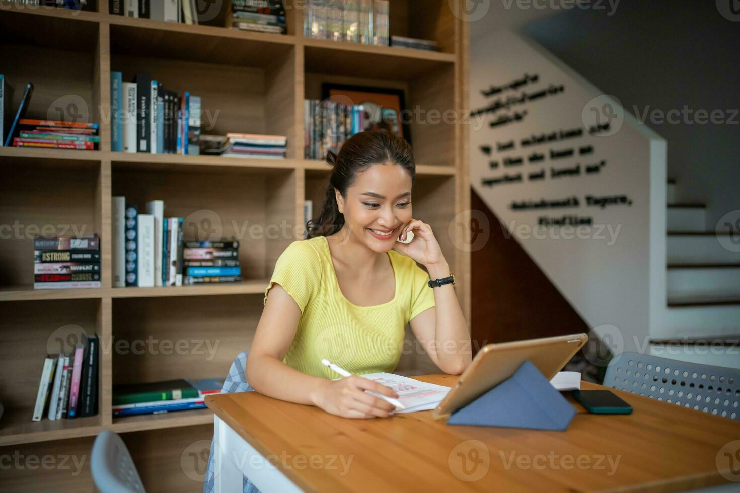 Female college student studying and working online with laptop and tablet at home photo