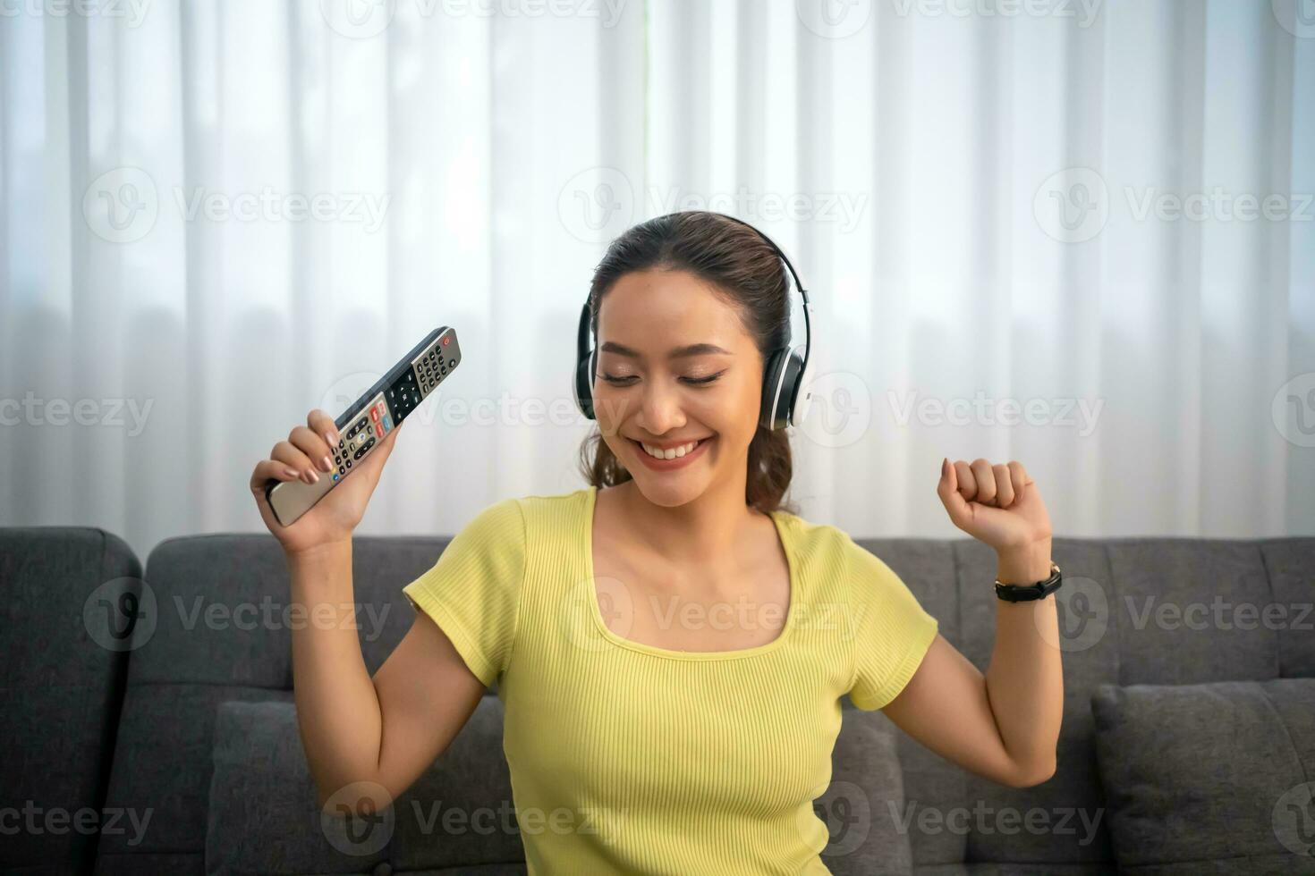 Woman wearing headphones and listening to music and singing happy at home on vacation. photo