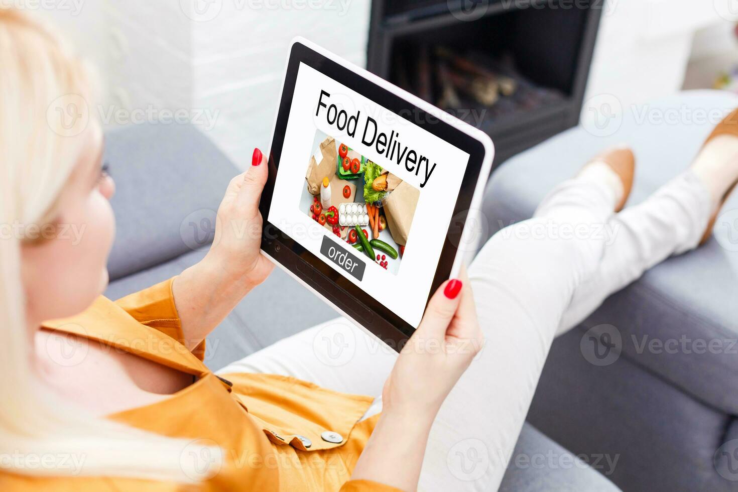 Girl ordering pizza online on smartphone, with table and coffee and plant in background photo