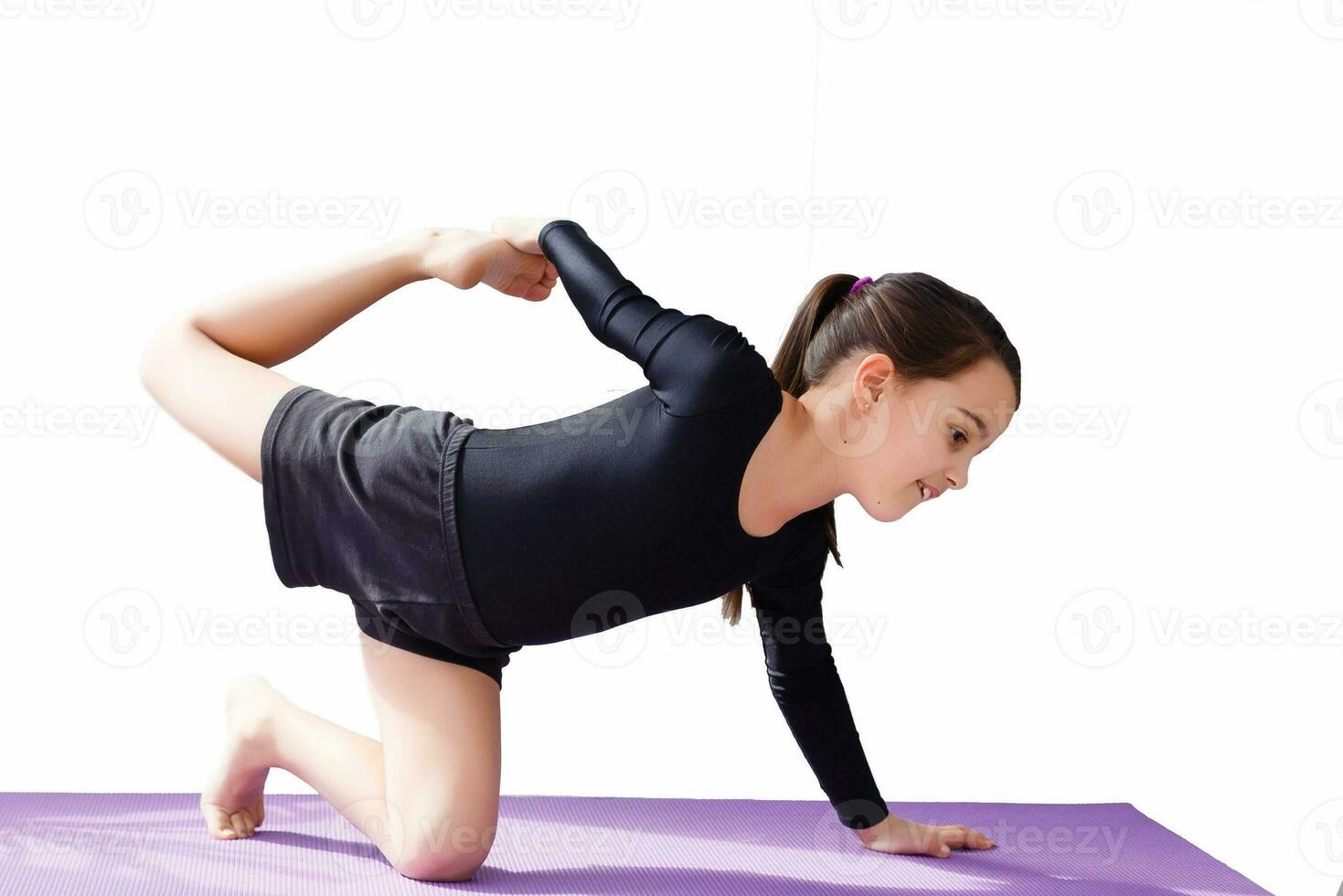 pequeño niña en un deportivo atuendo haciendo ejercicios puente en contra blanco antecedentes foto