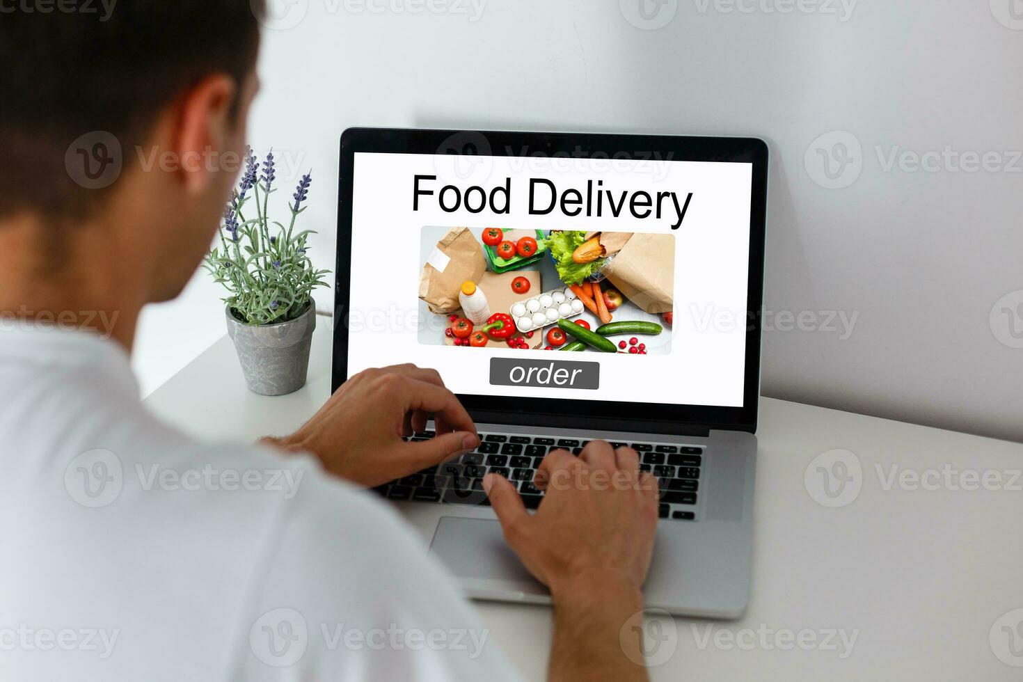 Man ordering take away food by internet with a laptop while lying at home. photo