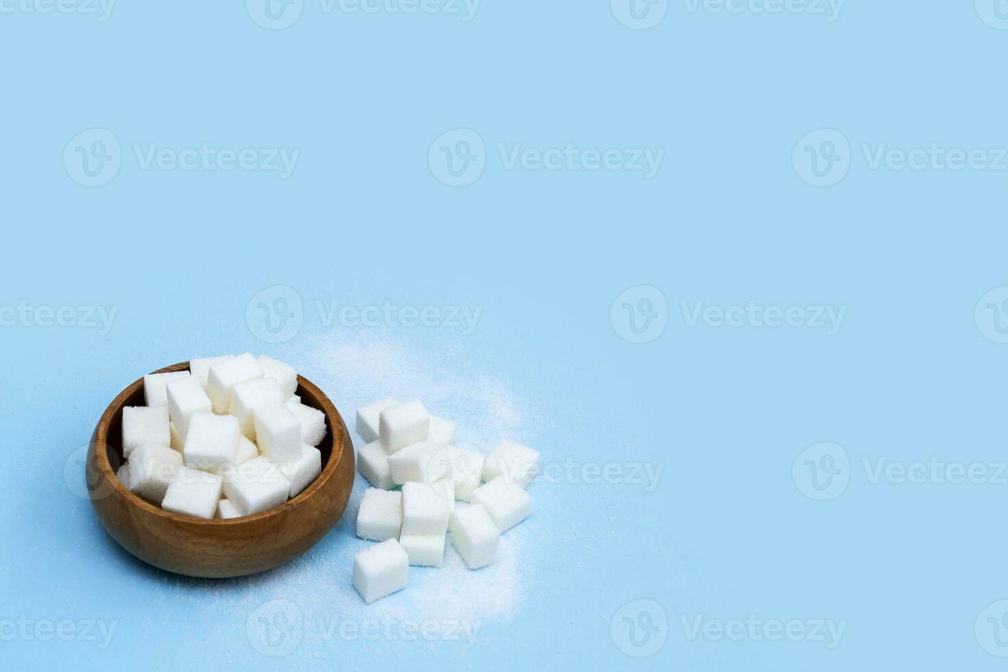 refined sugar in a wooden cup on a blue background with copy space photo