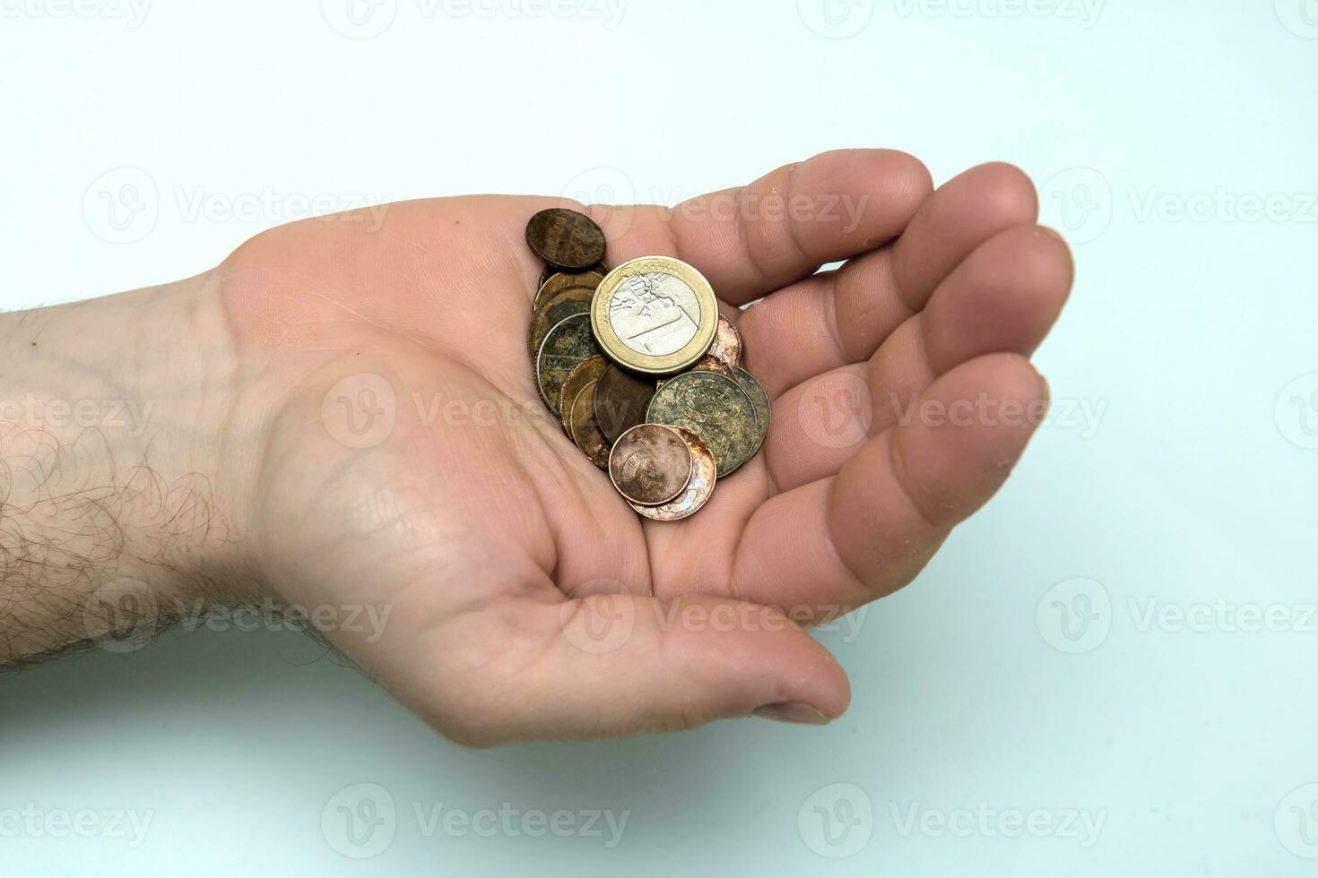 in a man's hand a handful of rusty coins with a coin of 1 euro photo