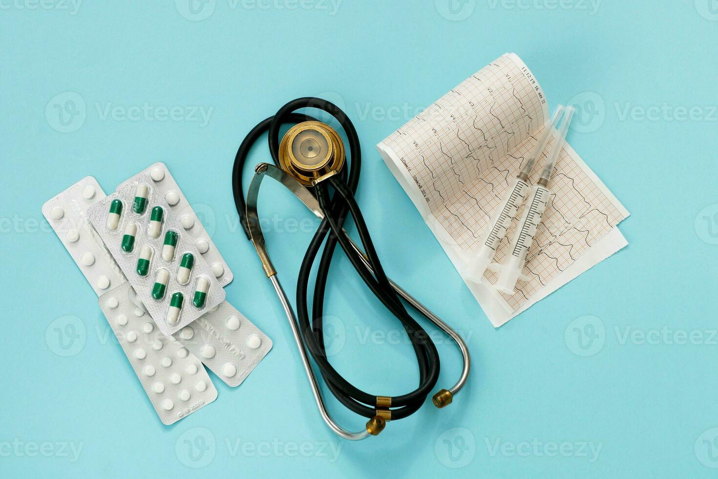 pills, phonendoscope, cardiogram, syringes on a blue background modern medicine photo