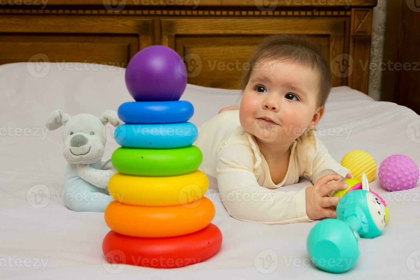 baby girl lying on the bed plays with toys with interest photo