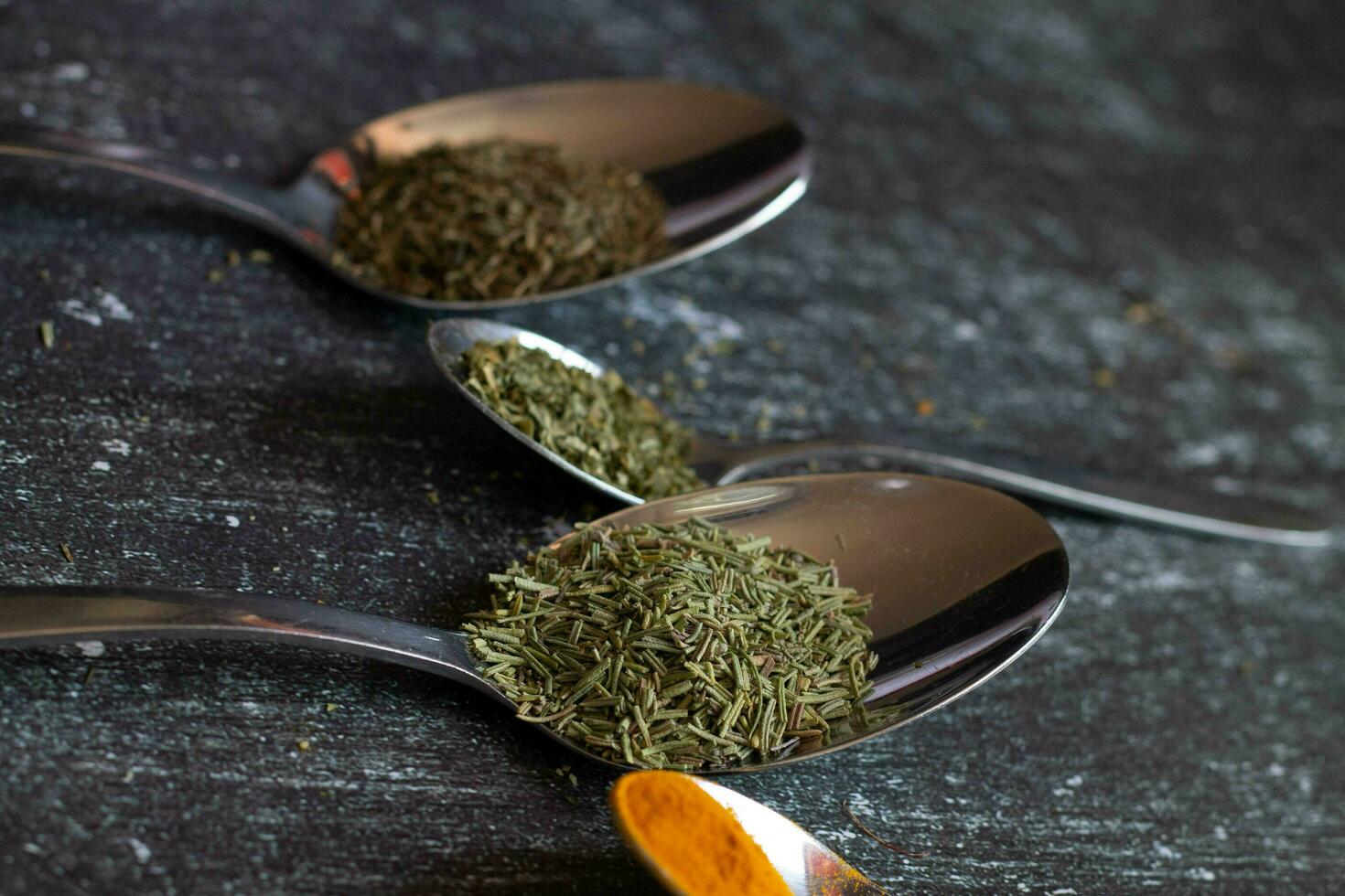 Spoons with spices and herbs on a black background. Food and cuisine ingredients. photo