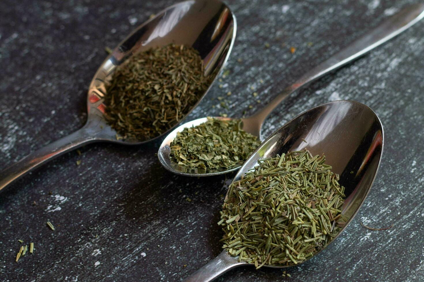 Spoons with spices and herbs on a black background. Food and cuisine ingredients. photo