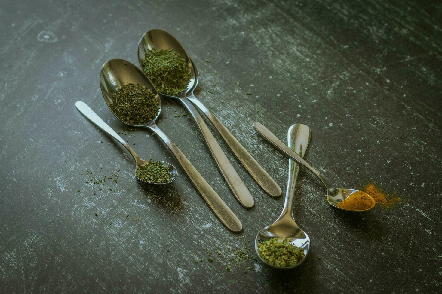 Spoons with spices and herbs on a black background. Food and cuisine ingredients. photo