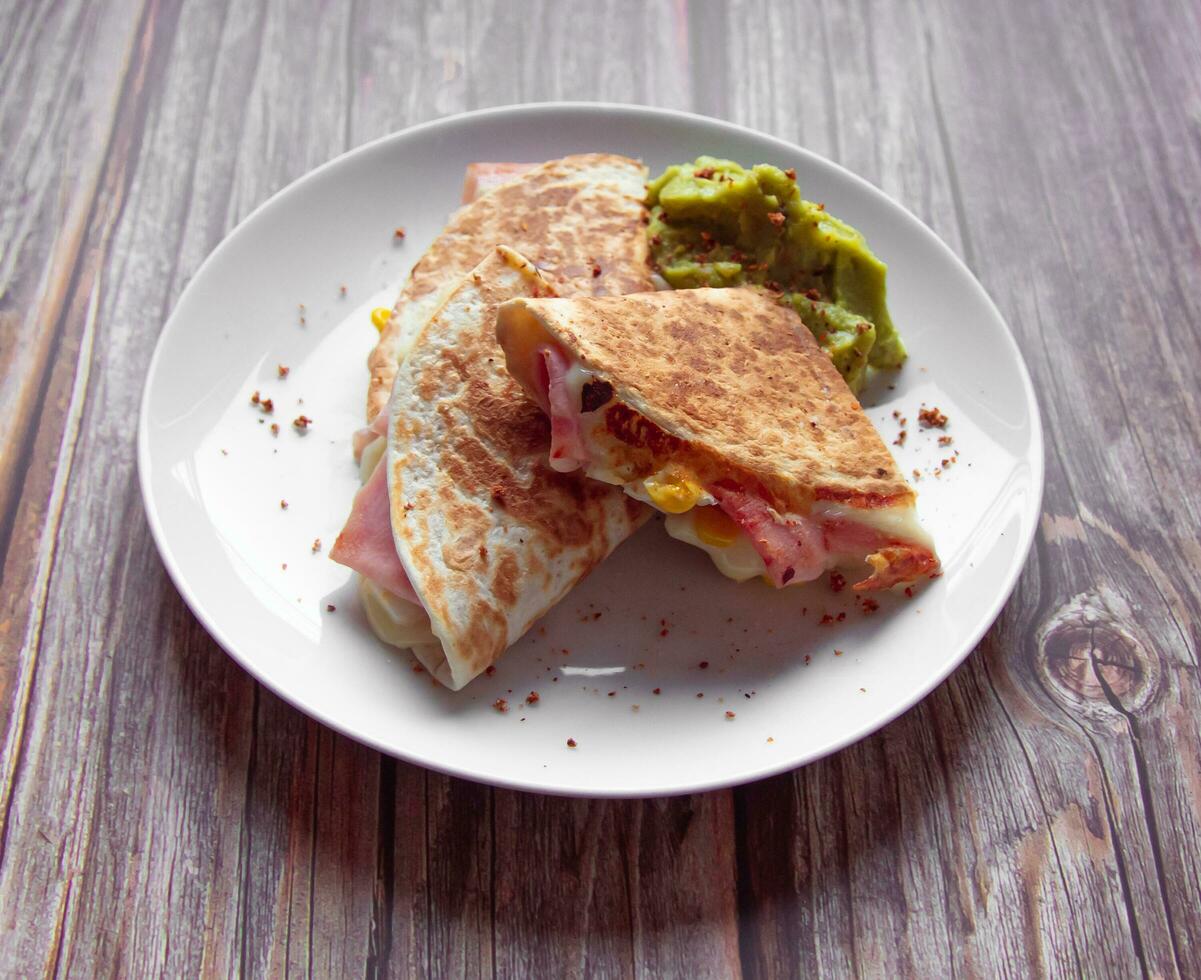 A plate of food with a quesadilla and guacamole on it. photo