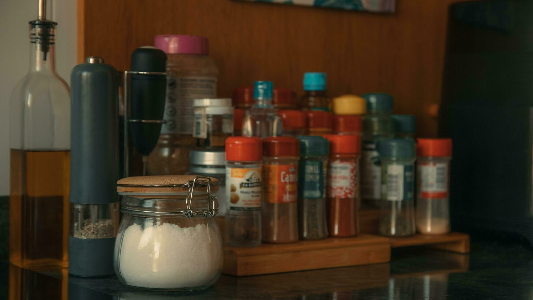 A spice rack with spices and a bottle of oil and salt photo