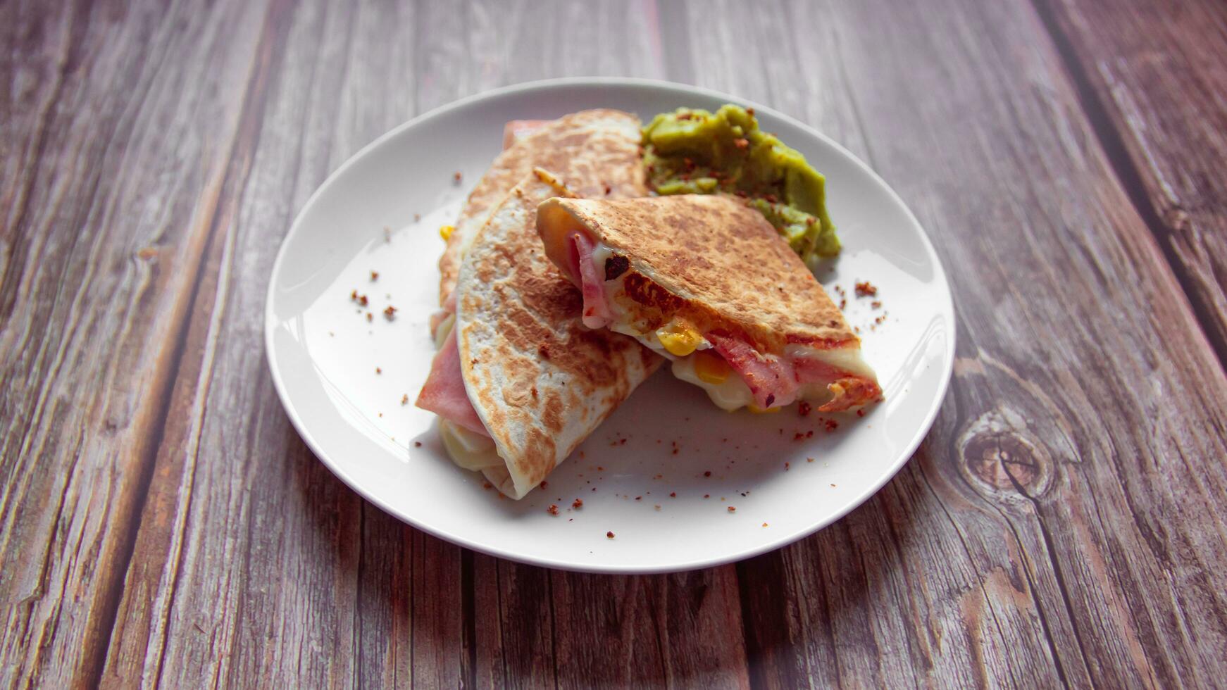 A plate of food with a quesadilla and guacamole on it. photo