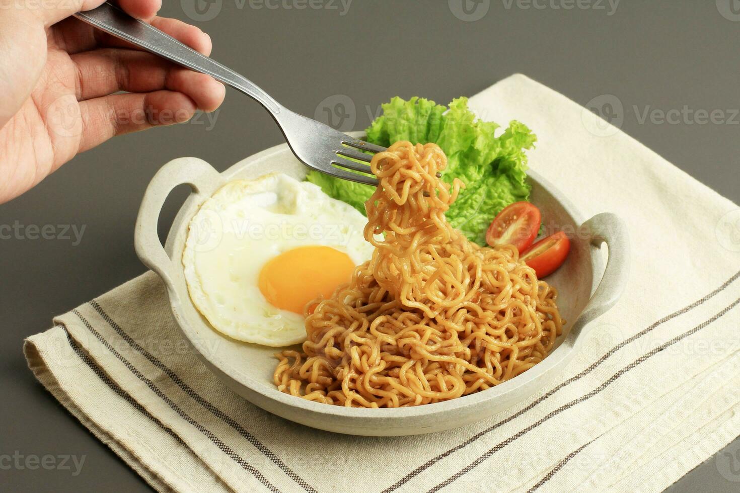 comer frito fideos indomie Goreng, tomar tallarines con tenedor. foto