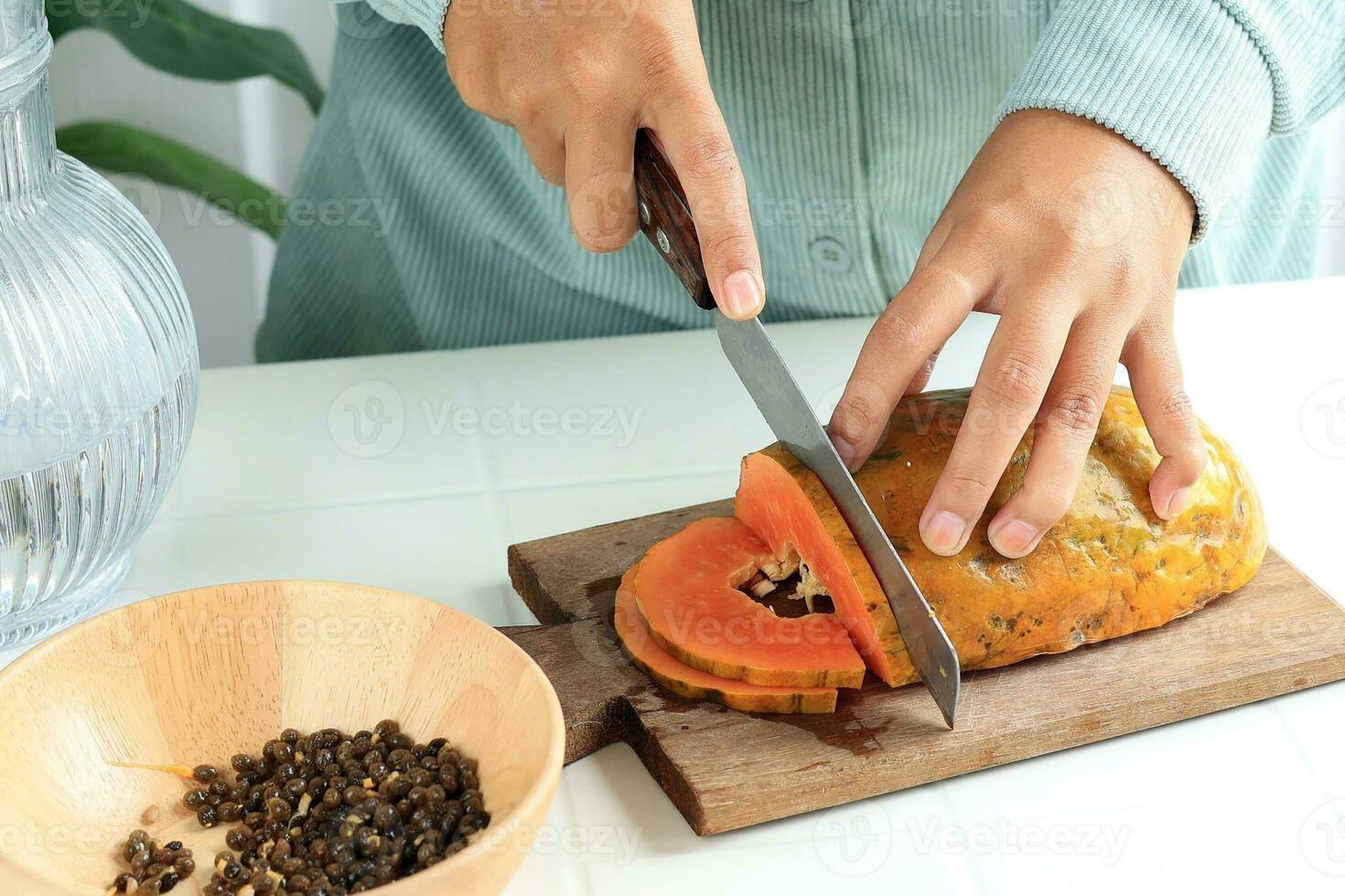 Hands Holding a Knife Slicing Over Ripe Papaya photo
