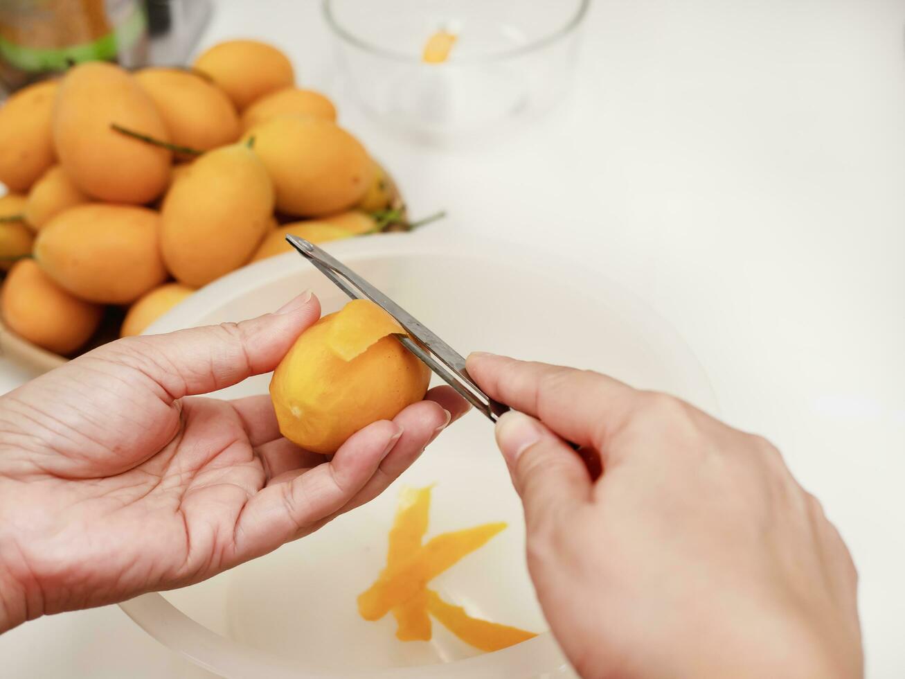 man peel ripe juicy peeled marian plum or plum mango over white kitchen background, thailand fresh delicious sweet asian famous tropical fruit photo